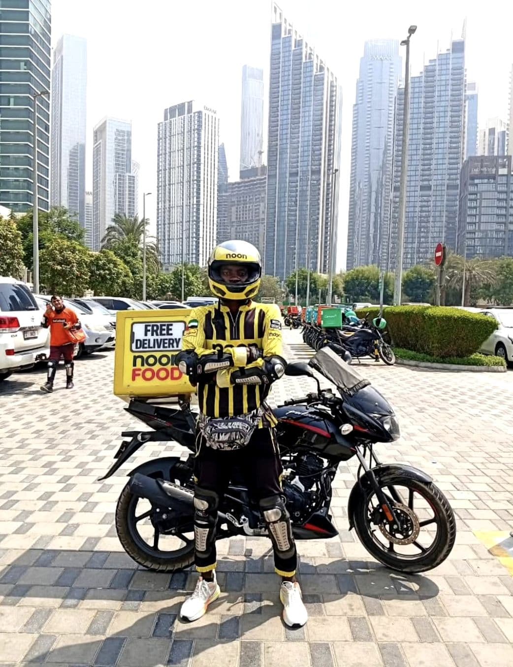 A real Nysaa delivery rider on the road for Noon against the Dubai skyline